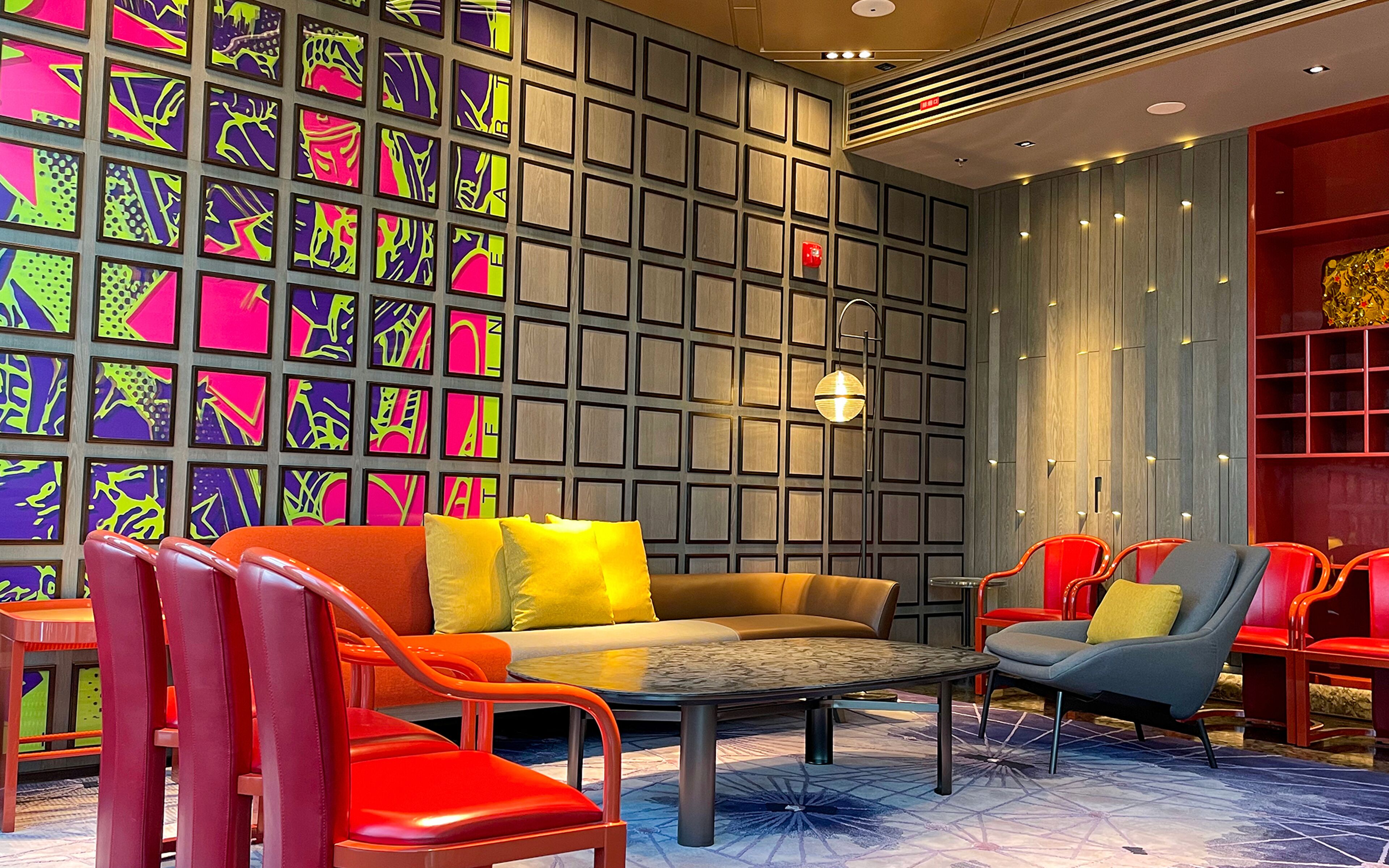 A modern lounge area with a sofa, chairs, and a patterned wall.