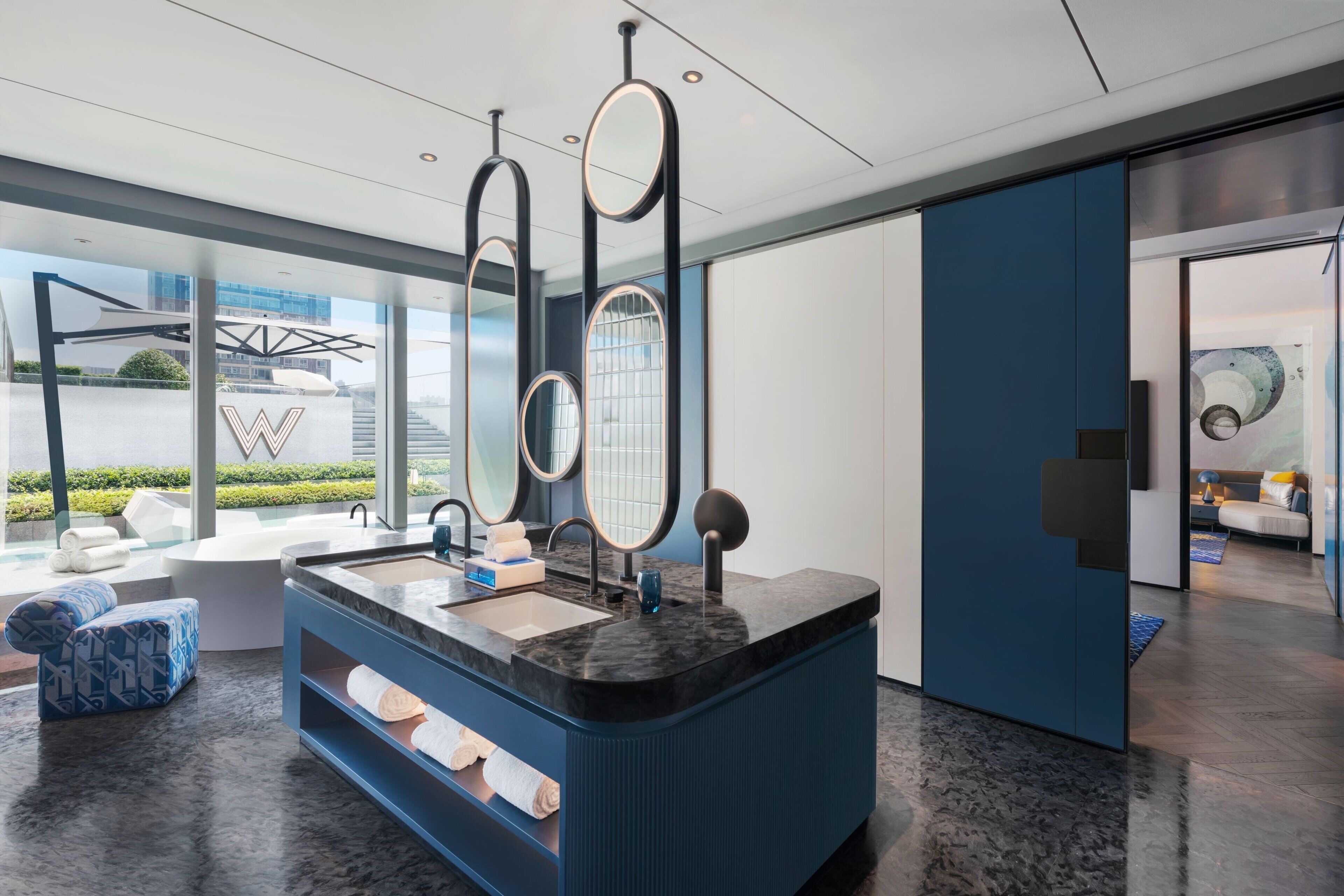 Une salle de bain moderne avec un grand lavabo, des miroirs et un mur d’accent bleu.