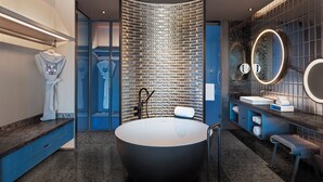 A modern bathroom with a large freestanding bathtub, a glass partition wall, and a vanity with a mirror.