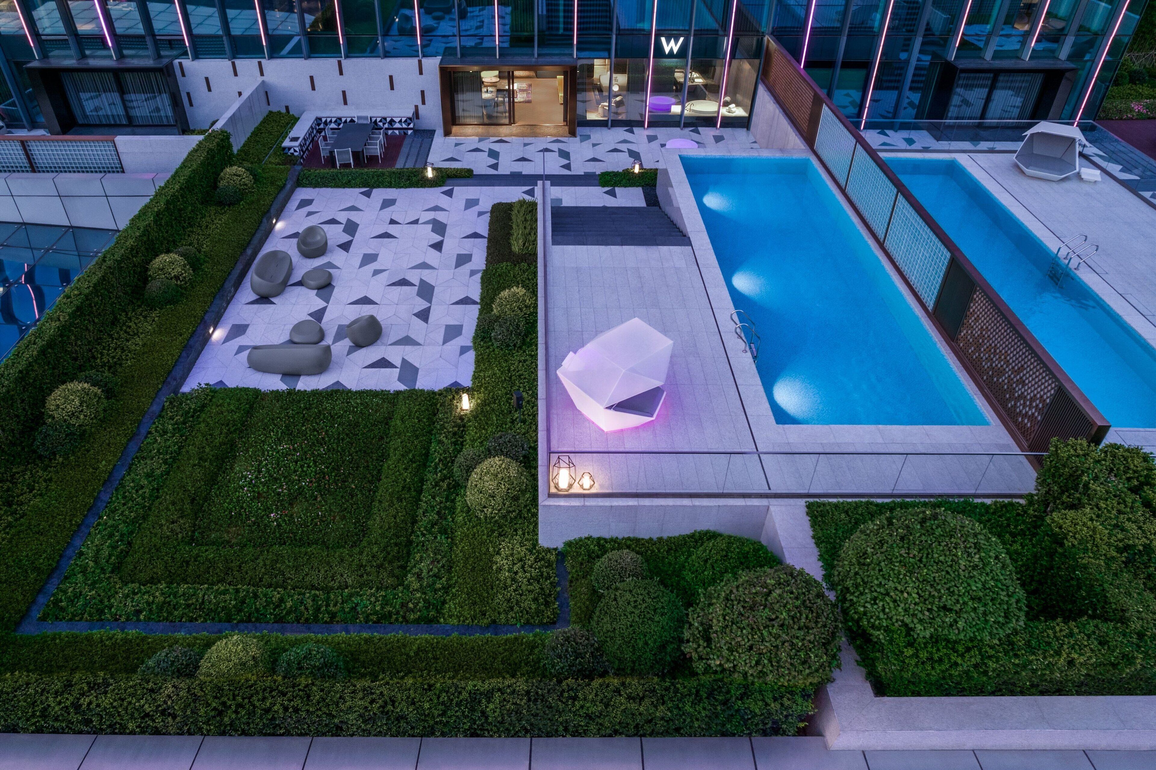 Un jardín en la azotea con piscina, zonas de estar y un restaurante.