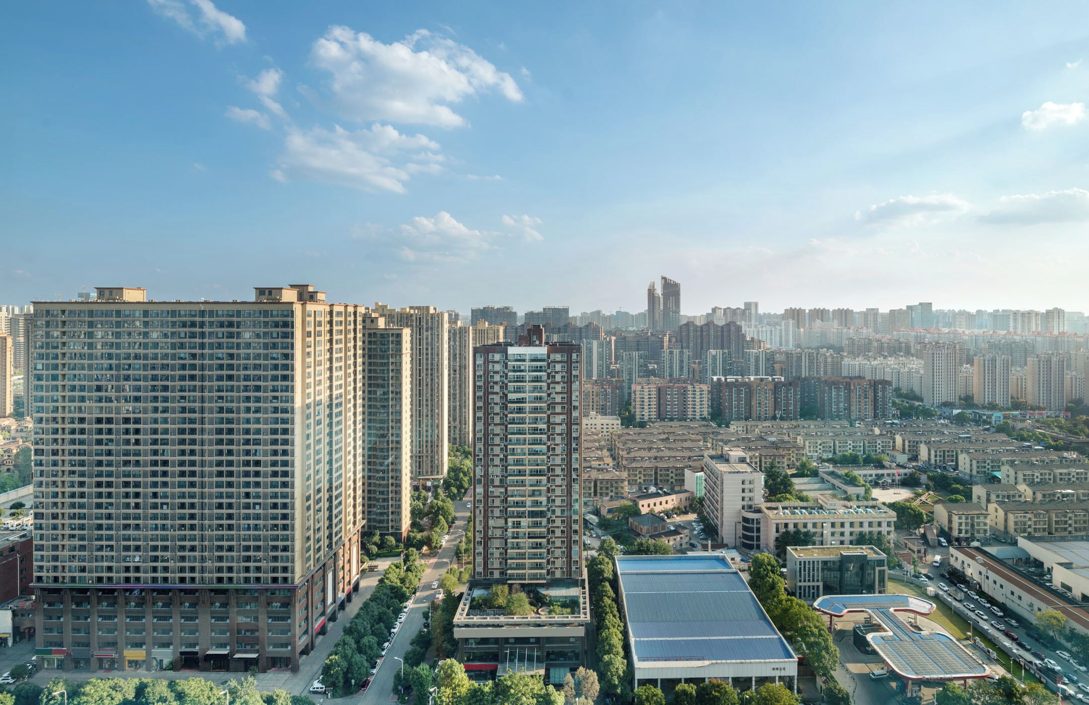 A high-rise building with a grid of windows, surrounded by other buildings and a clear sky.