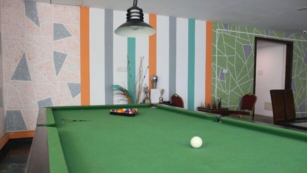 A pool table with balls, a lamp, and striped walls. - Citrus Hotels Sriperumbudur (Sriperumbudur)