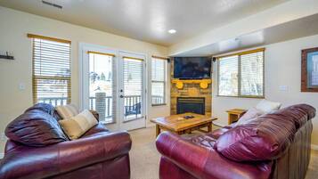 A living room with leather sofas, a fireplace, and a television mounted above it.