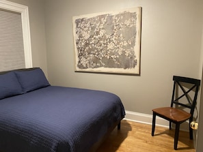 A bedroom with a bed, a chair, and a painting on the wall.