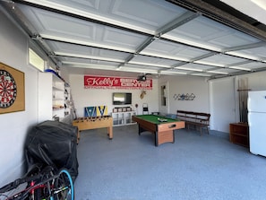 Eine Garage mit Billardtisch, Dartscheibe, Kicker und einem Fahrrad.