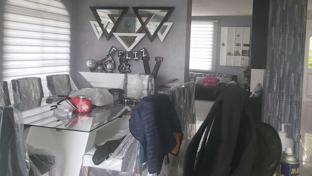 Ett rum med en modern takdesign, ett skrivbord i glas och en soffa.