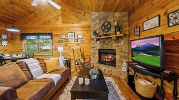 A cozy cabin interior with a wooden interior, a fireplace, a television, and a dining area.