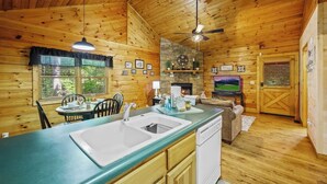 L’intérieur d’un chalet en bois comprend une cuisine, un coin repas et une cheminée.