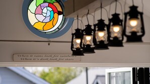 A room with a stained glass window, a ceiling light fixture, and a view of the outside through a glass door.