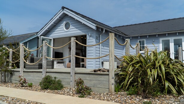 A coastal building with a covered porch, wooden railings, and a stone pathway.