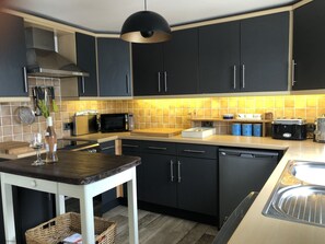 A modern kitchen with dark cabinets, a microwave, a toaster, and a sink.