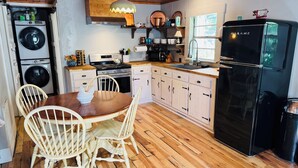 A kitchen with wooden flooring, a dining table with chairs, a refrigerator, a stove, and a washing machine. - Waterfront Cabin on trophy trout stream, fire pit, smart tv, fireplace (Ellijay)
