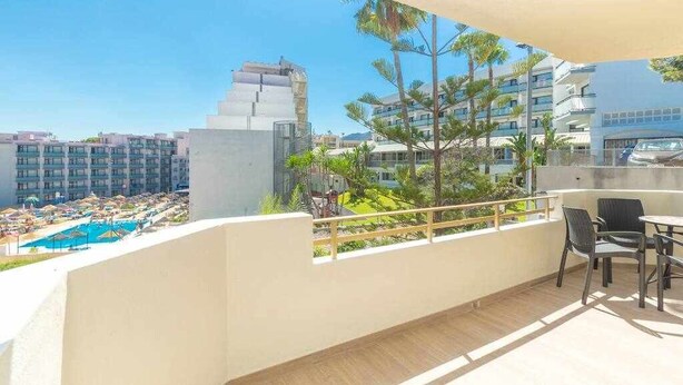 Un balcon donnant sur une piscine et les bâtiments environnants.