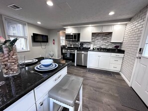 A modern kitchen with white cabinets, black countertops, stainless steel appliances, and a tiled backsplash. - 100% renovated House 8 minutes to downtown (Pittsburgh)