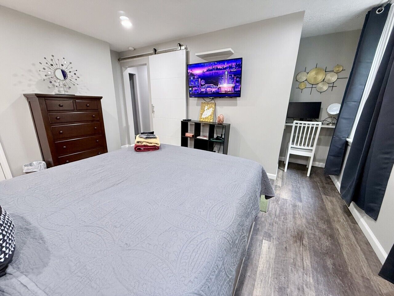 Une chambre à coucher avec un lit, une commode, une télévision et une chaise.