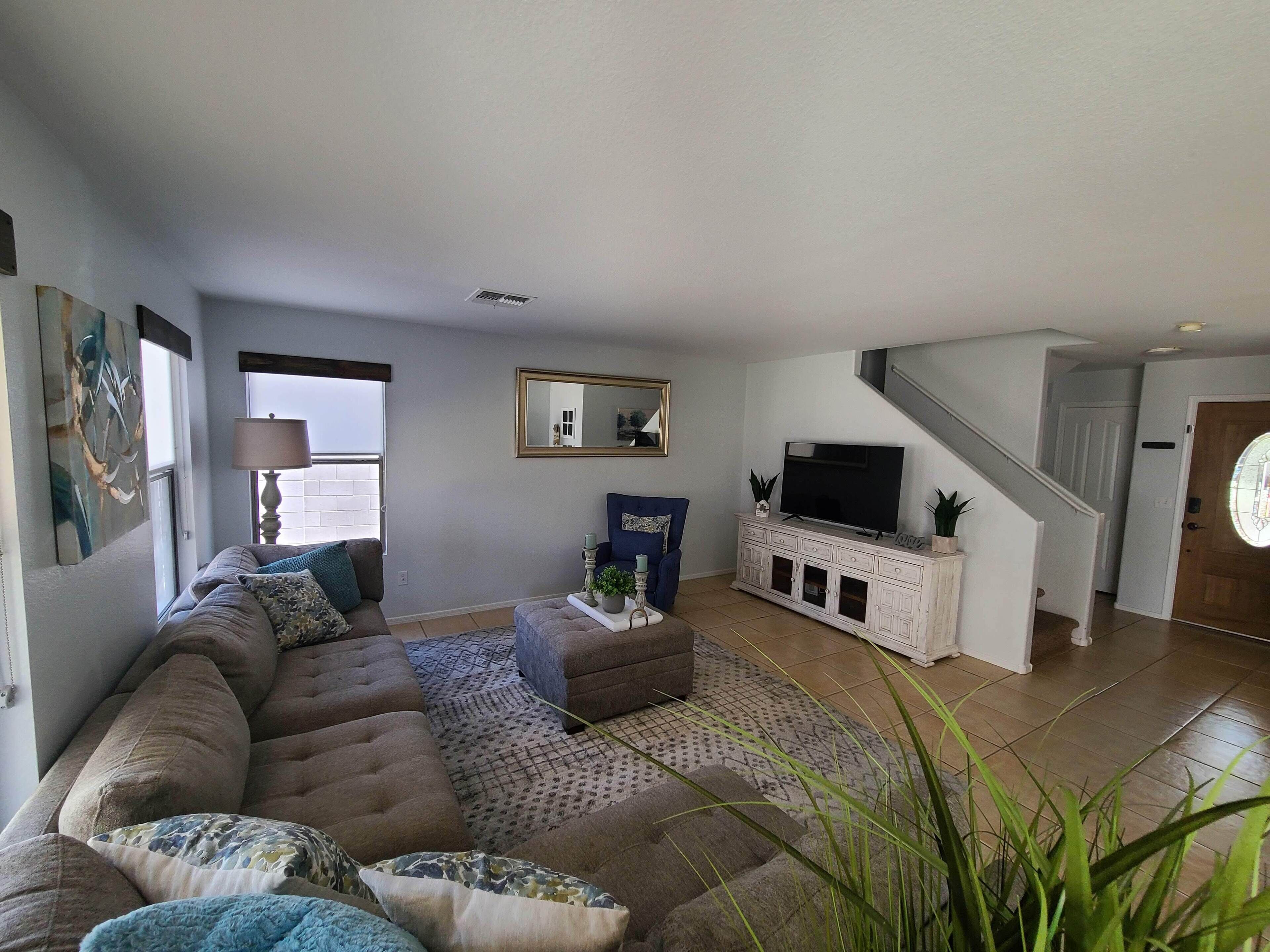 A modern living room with a sectional sofa, a flat-screen TV, and a staircase leading to another level.