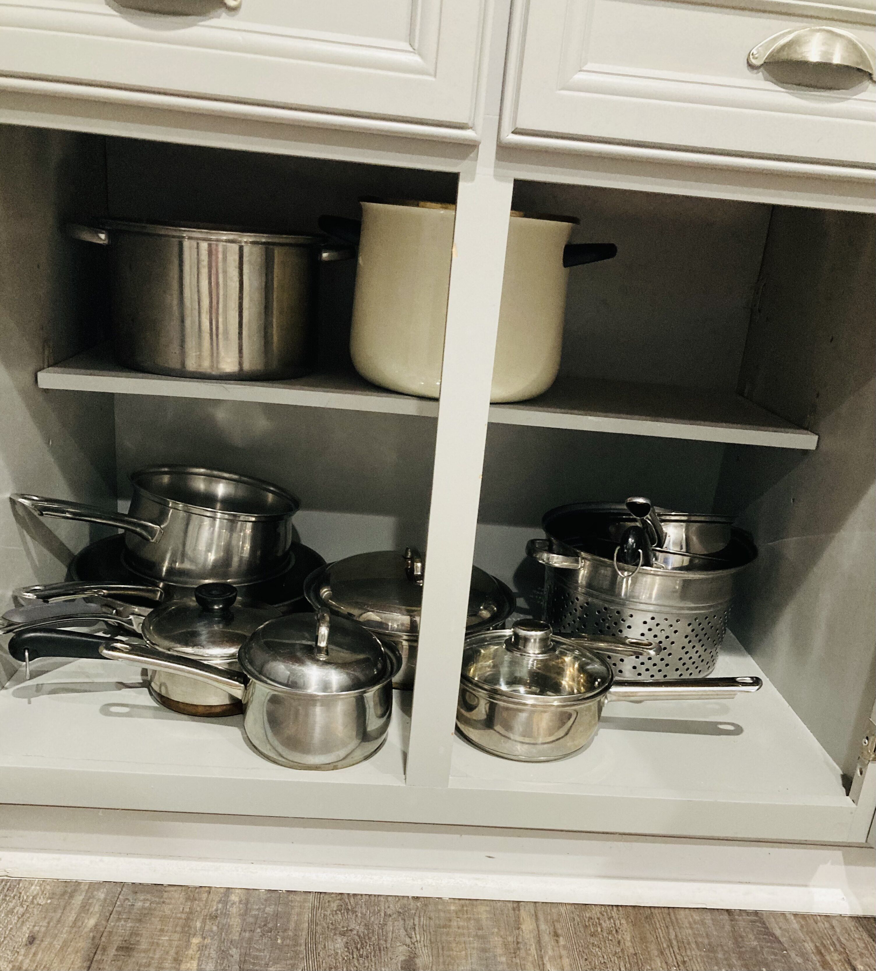 A kitchen cabinet with multiple shelves holding various kitchen utensils and cookware.