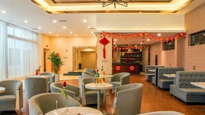 A hotel lobby with round tables and sofas, a reception desk, and a decorative red banner. - Ji Bin Hotel (Changsha)