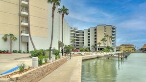 Un hotel frente al agua con varios pisos, un muelle y palmeras.