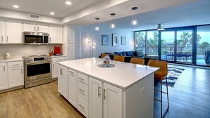 Una cocina moderna con armarios blancos, electrodomésticos de acero inoxidable y una isla central.