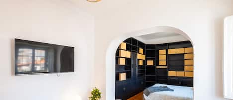 A modern living room with a flat-screen TV, a white console table, a sofa, and a built-in bookshelf.