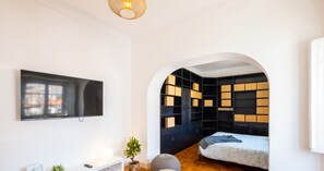 A modern living room with a flat-screen TV, a white console table, a sofa, and a built-in bookshelf.
