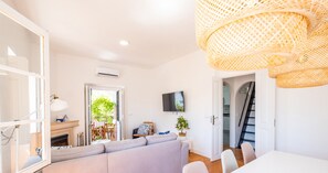 A modern living room with a sofa, dining table, and a TV mounted on the wall.