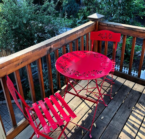 A wooden deck with a red metal table and chairs. - Ft Collins Tree Top Loft in Center of Old Town (Fort Collins)