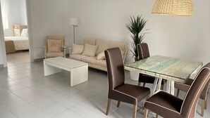 Un soggiorno moderno con un tavolo da pranzo in vetro, poltrone in pelle marrone, un divano beige e un tavolino da caffè bianco.