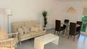 Un soggiorno moderno con un divano, poltrone, un tavolino da caffè e un'area pranzo con sedie e tavolo.