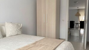 Una camera da letto con un letto, un armadio e un ingresso che conduce a una sala da pranzo.