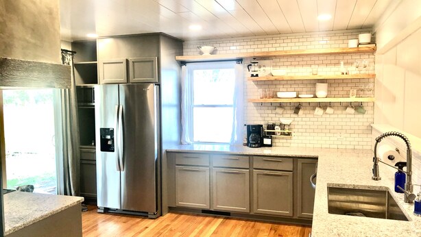 A modern kitchen with stainless steel appliances, wooden flooring, and a window providing natural light. - Stay at the Lazy Llama House with Self Check-In (Lincoln)