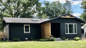A two-story house with a dark exterior, a sloped roof, and a small front porch. - Stay at the Lazy Llama House with Self Check-In (Lincoln)