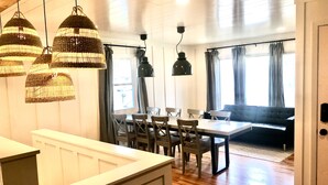 A dining area with a table and chairs, a bench, and hanging wicker lamps. - Stay at the Lazy Llama House with Self Check-In (Lincoln)