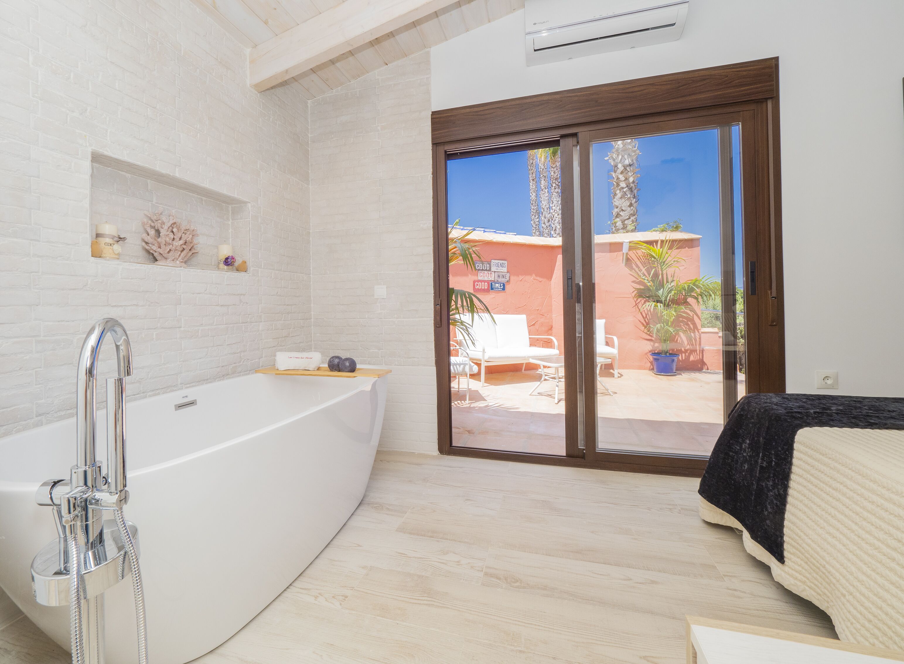 Une salle de bain moderne dotée d’une grande baignoire, d’une douche et d’une porte coulissante en verre donnant sur un espace extérieur aménagé pour se détendre.