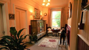 A room with a wooden cabinet, a chair, a table, and a window with curtains. - Kingscroft (Buxton)