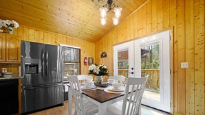 A wooden cabin interior with a kitchen, dining area, and a sliding glass door to the outside. - Gatlinburg cabin, 3 bed 2 bath, hot tub, no scary roads, PERFECT location (Gatlinburg)