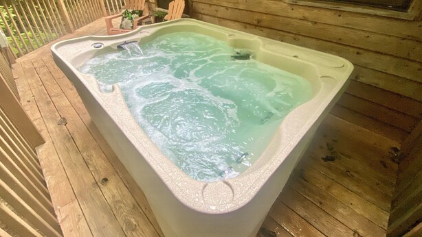 A hot tub on a wooden deck with a wooden cabin in the background. - Gatlinburg cabin, 3 bed 2 bath, hot tub, no scary roads, PERFECT location (Gatlinburg)