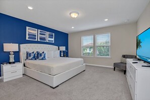 A bedroom with a large bed, a nightstand, a dresser, and a TV.
