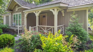 A two-story house with a porch, a front door, and a small garden area with various plants and flowers. - Beautiful New Cottage w/ Endless Hilltop Views (Paoli)