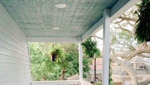 Une véranda avec des chaises en plastique bleues et une balustrade blanche.