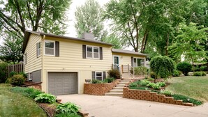 A two-story residential house with a front garage, a small front porch, and a landscaped front yard with a brick pathway leading to the entrance. - Centrally located, spacious, updated home with room to Entertain! (Sioux Falls)