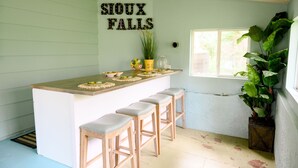 A kitchen with a bar area, a sign reading "SIOUX FALLS", and a large plant. - Centrally located, spacious, updated home with room to Entertain! (Sioux Falls)