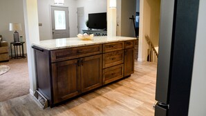 A spacious kitchen with a large island, wooden cabinets, and pendant lighting. - Centrally located, spacious, updated home with room to Entertain! (Sioux Falls)
