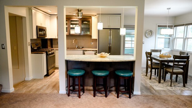 A modern kitchen with a central island, bar stools, and a dining area with a chandelier. - Centrally located, spacious, updated home with room to Entertain! (Sioux Falls)