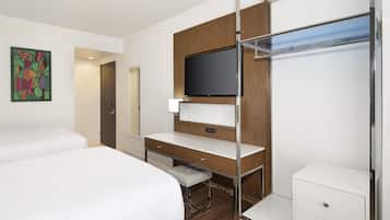 Ein Hotelzimmer mit Bett, Schreibtisch mit Fernseher, Schrank und einem Bild an der Wand.