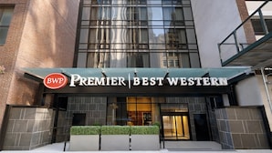 Een hotel ingang met een modern gevelontwerp, grote ramen en een bord waarop 