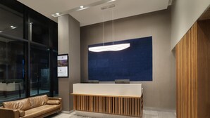 Een modern receptiegebied met een houten receptiebalie, een leren bank en een grote blauwe wand met een structuurpatroon.
