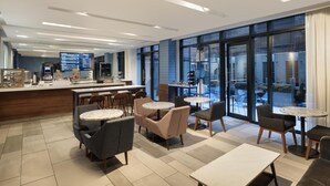 Een moderne hotel lobby met een bar, zithoeken en grote ramen met uitzicht.