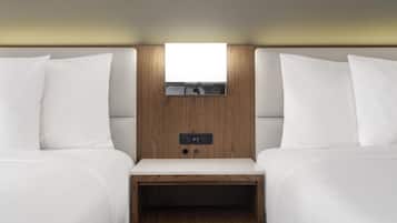 Quarto com duas camas, mesa de cabeceira, luminária fixada na parede e tomadas elétricas.